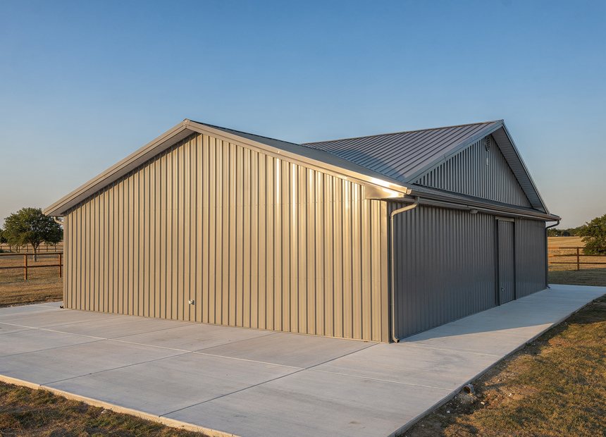 Custom red-iron metal building with roll-up doors on a slab near San Antonio, TX